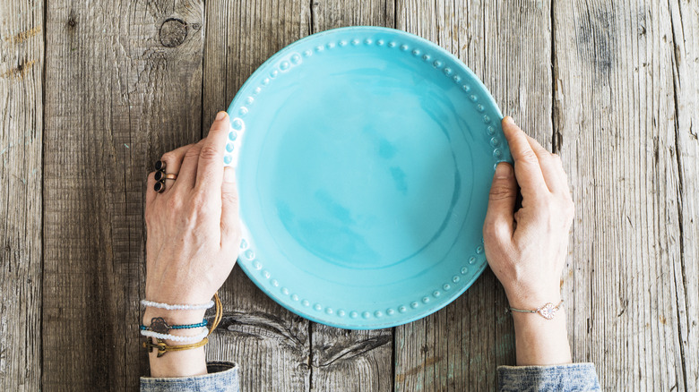 Woman holding blue plate with wood background