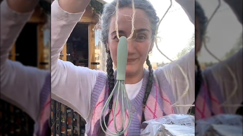 Woman stringing whisk bird feeder with twine outdoors
