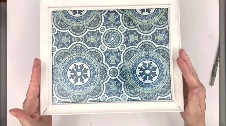 Woman assembling top of two-tier Dollar Tree organizer with eccentric blue pattern