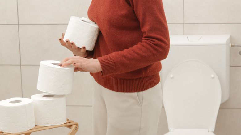 Woman organizing toilet paper rolls inside bathroom