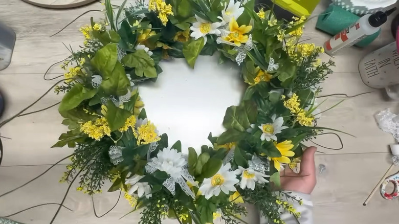 Finished artificial floral centerpiece with yellow flowers, greenery, ribbon, and metal center
