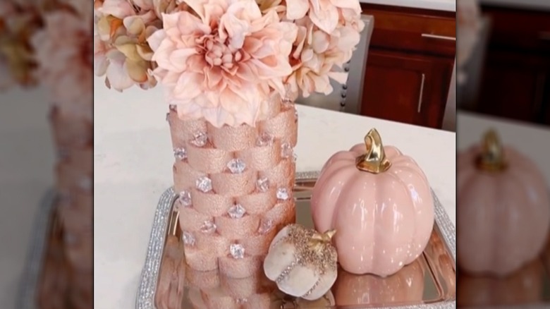 Flower display made from a flexible cutting board and a pool noodle cut into semi circles painted pink with gemstone accents
