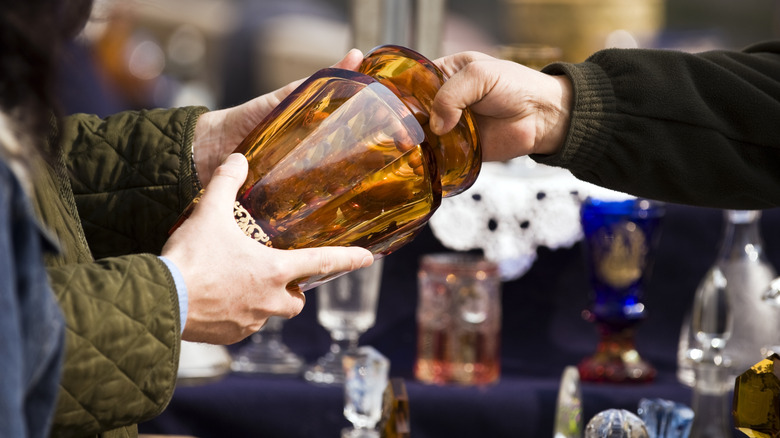 person being handed a brown glass vase