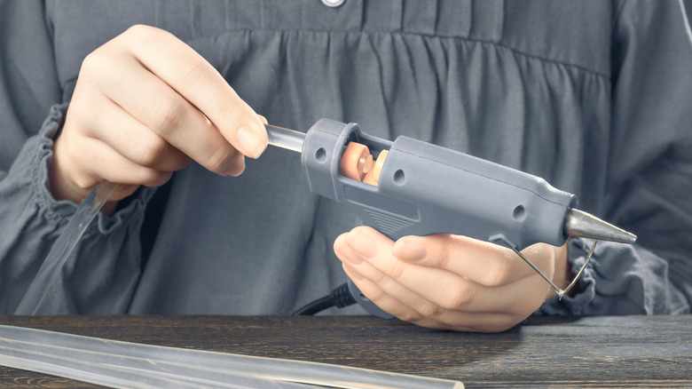 A person loading glue sticks into a glue gun