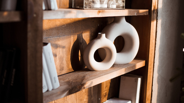 A wooden bookshelf with decorative, circular vases