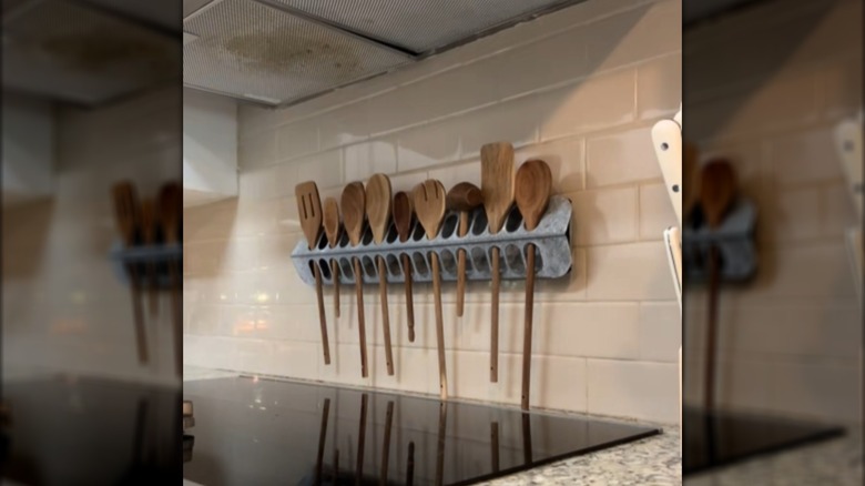 Chicken feeder holding wooden utensils on a tile backsplash above a stove