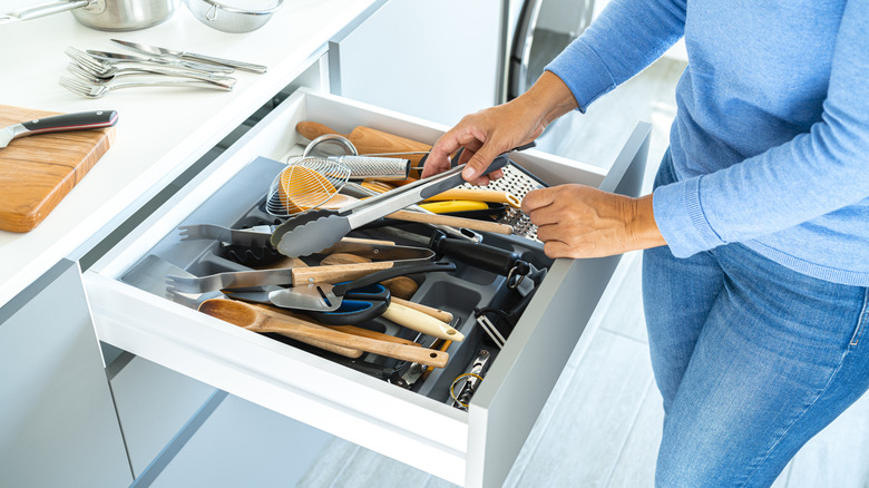 Person organizing kitchen utensils in a drawer