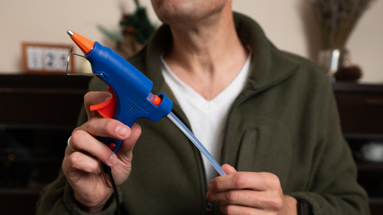 A person loading a hot glue gun