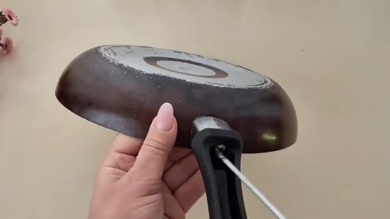 Person removing the handle from an old skillet