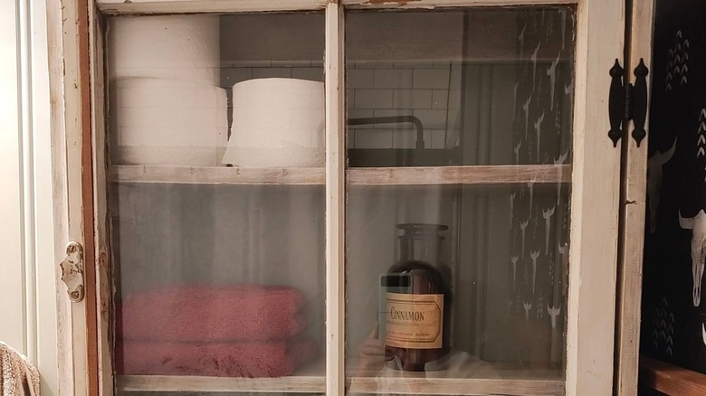 An upcycled cabinet holding toilet paper and other bathroom necessities.