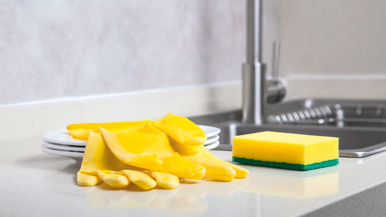 Yellow gloves and sponge on side of kitchen sink