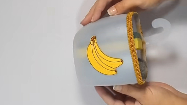 A hanging kitchen sponge holder with a banana sticker