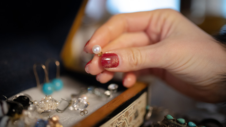 Woman taking pearl earring from jewelry box