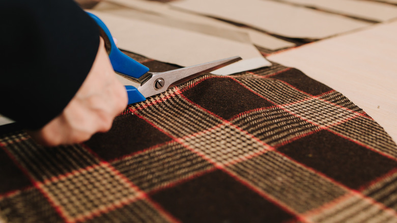 Woman cutting checkered fabric with scissors