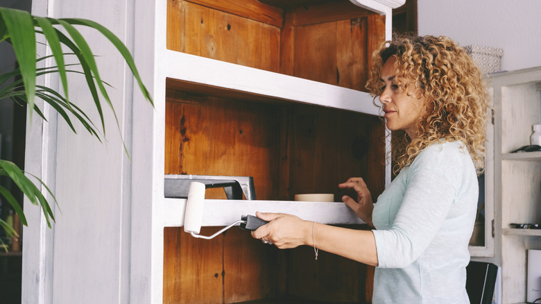 Woman painting a wooden cabinet white