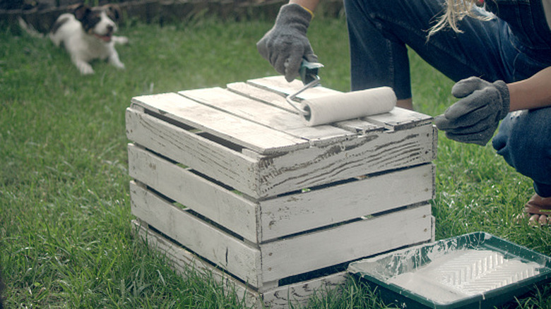 woman paints a wooden crate