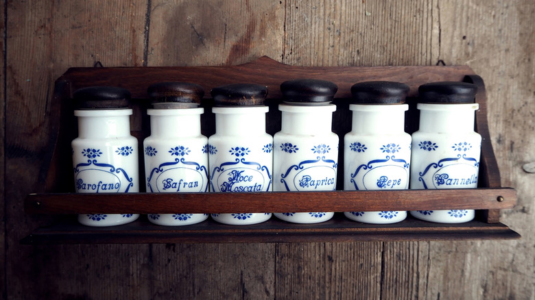 vintage wood spice rack mounted on a wall with matching blue and white spice containers