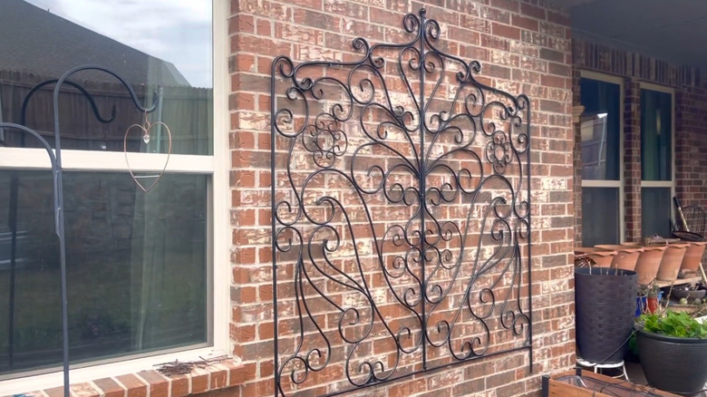 Ornate headboard hung on a wall to serve as a trellis