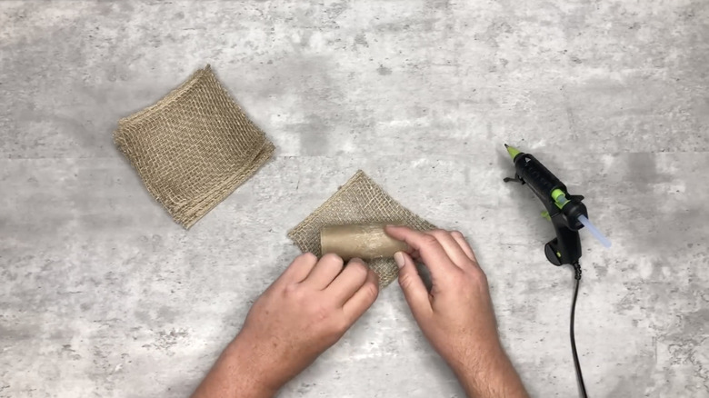 Hands doing DIY with toilet paper roll and burlap