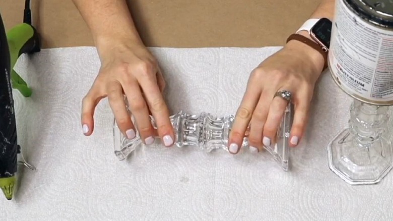 Woman gluing Dollar Tree candleholders together to make countertop tray