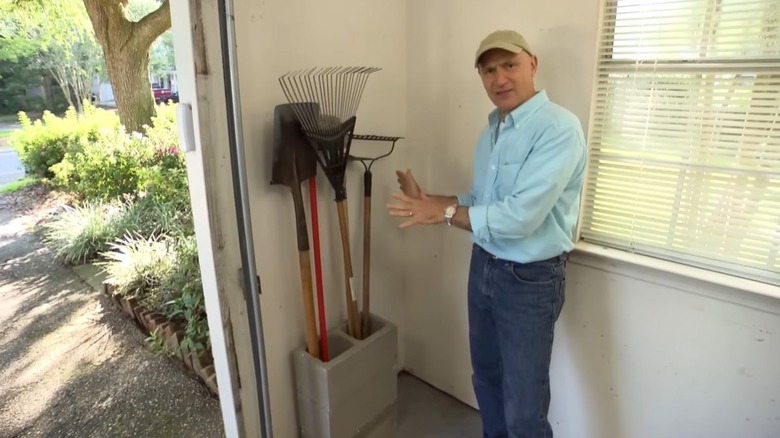 Man showing tool organizer in garage made from concrete blocks