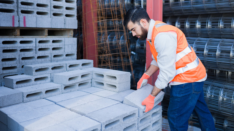 A person stacking concrete blocks in a store