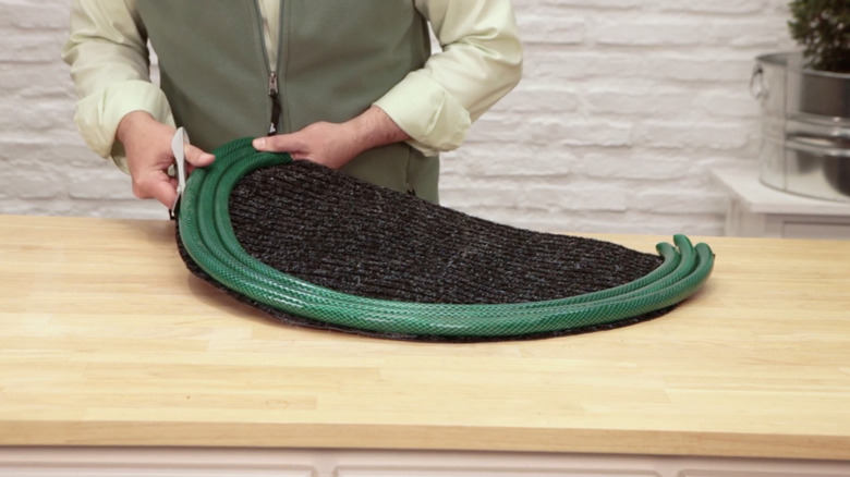 Someone DIYing a garden hose rug using scissors
