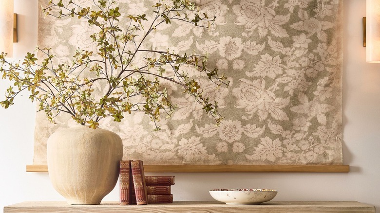 Pottery Barn vase with faux greenery stems on a console