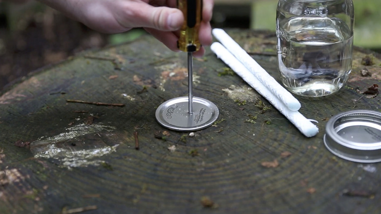 mason jar DIY, person making hole in lid