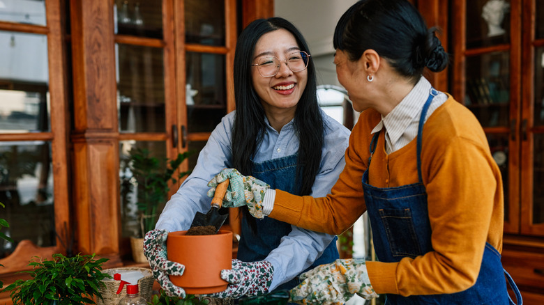 Two women smiling while holding terracotta pots