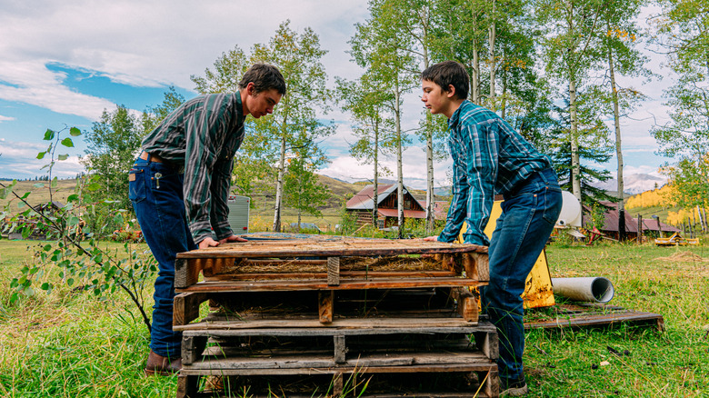 A father and son team-lift a wood pallet