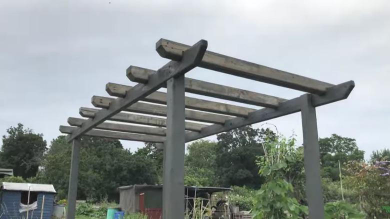 A DIY pergola made from old wooden pallets in a garden.
