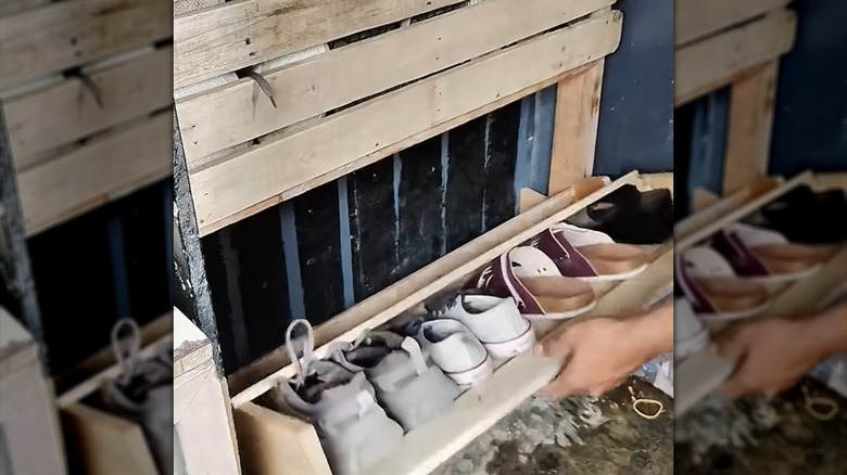 man operating the bottom drawer of a DIY wood pallet tilt-out shoe storage compartment