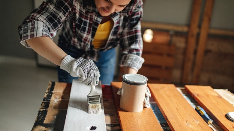 Person painting wood pallet boards with white paint