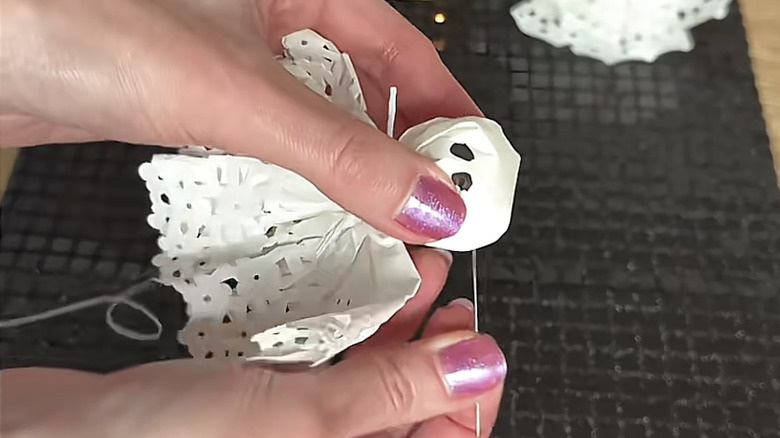A woman assembling DIY ghost garland made out of white doilies