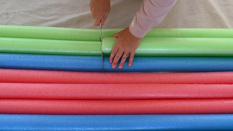 A woman cutting into a couple of pool noodles for a DIY