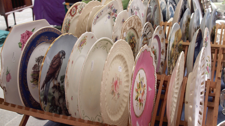 Racks of vintage plates at outdoor market.