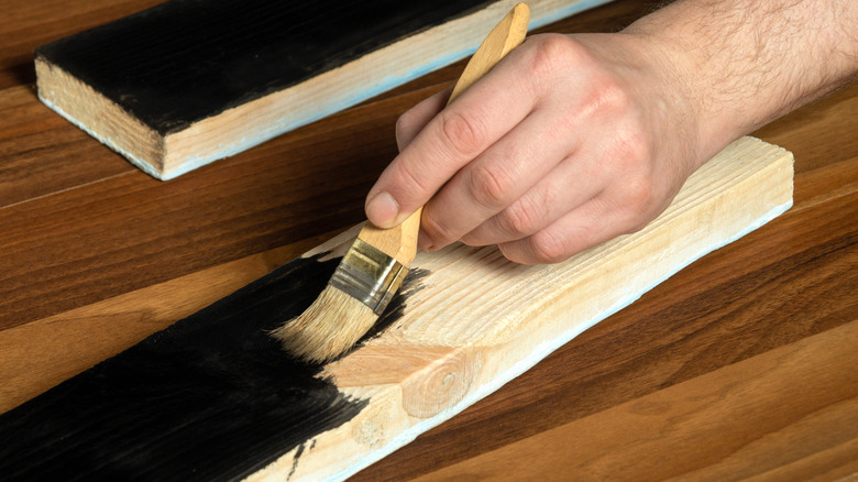 Hand painting a wood plank black