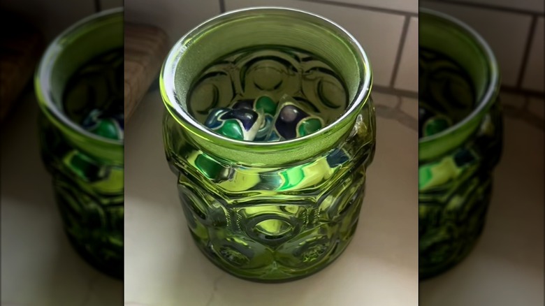 Green L.E. Smith canister jar filled with dishwasher pods beside sink on kitchen countertop
