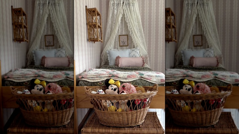 A little girl's cottagecore bedroom with a thrifted lace DIY canopy, a floral bed, and a basket of stuffed animals