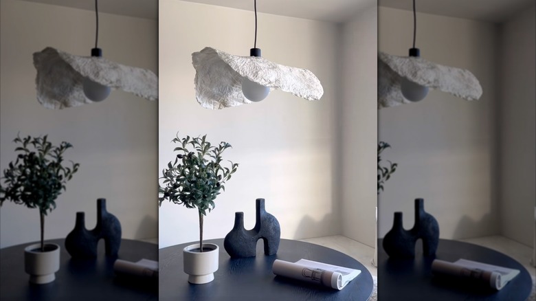 An organic pendant light hangs over a black dining room table