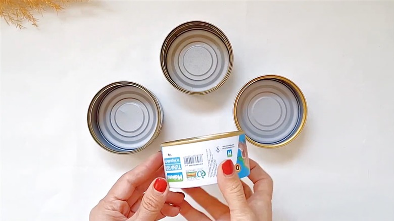 Person holding using empty tuna cans for crafting
