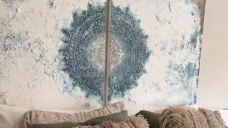 A close up of a headboard made from stretched canvases with a medallion print in the center.