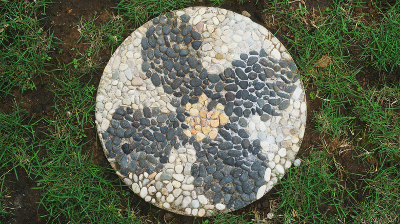 concrete paver on grass made with stones arranged in a flower pattern