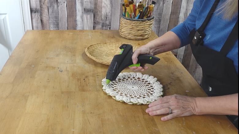 Woman hot-gluing lacey fabric doily on rustic wood table