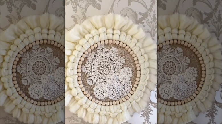 DIY boho doily wreath with fabric and wood bead edges on ornate vintage wall