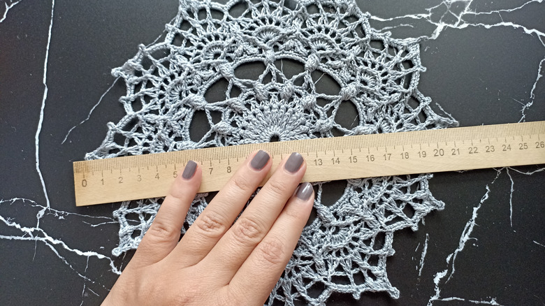 Someone holding a ruler over a doily
