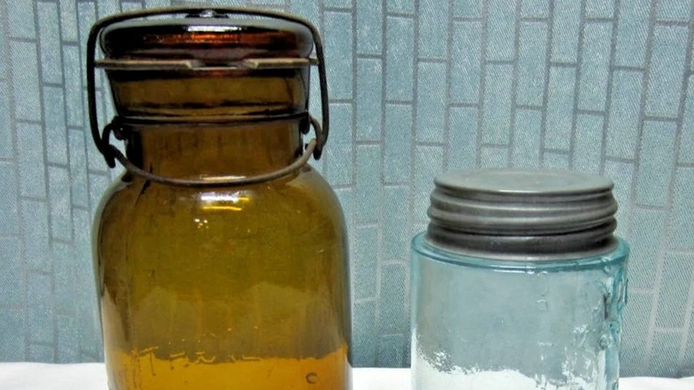 An amber lightning jar next to an older clear mason jar