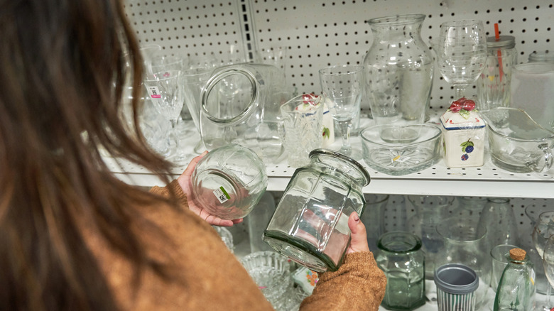 A person looks at a bunch of glass jars in a thrift store
