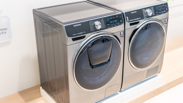 Side-by-side gray washer and dryer from Samsung sitting on a raised platform.